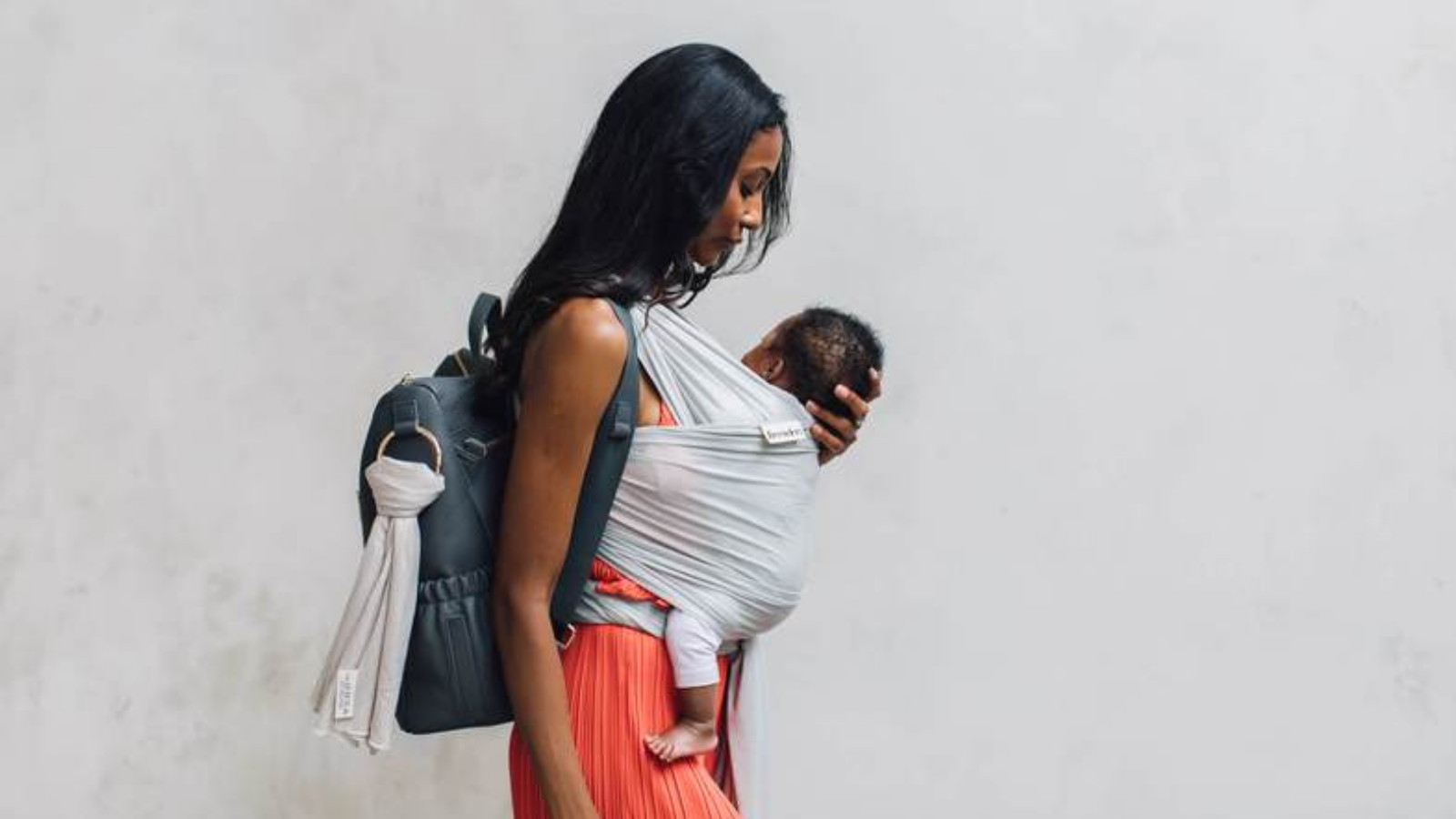 Woman carries baby on her front in the Freerider baby sling, side view