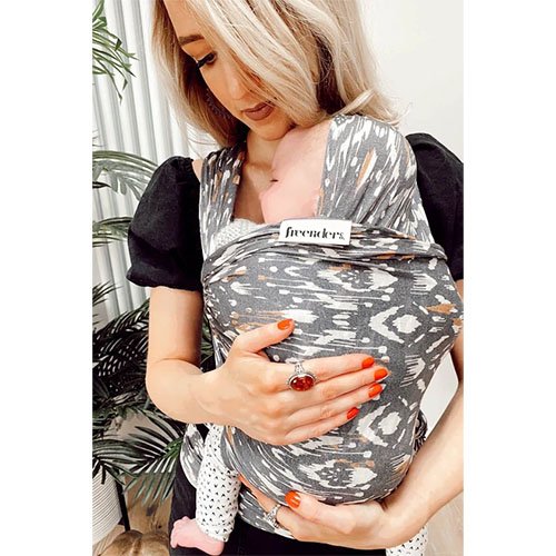 Woman carries baby on her front in the Freerider baby sling in Hex print