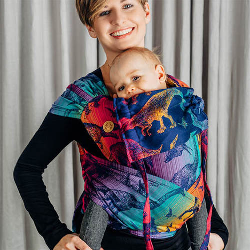 Woman carrying baby in Lenny Lamb Wrap Tai baby carrier in Jurassic Park New Era dinosaur fabric