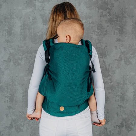Woman carries toddler on her back in Lenny Lamb Preschool carrier in Emerald fabric, back view