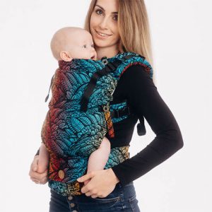 Woman carries baby facing towards her in Lenny Lamb LennyUpgrade Baby Carrier in colourful Wild Soul Daedalus fabric