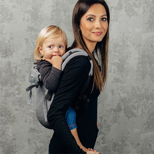 Woman carries baby on her back in Lenny Lamb Onbuhimo baby carrier in Little Herringbone Ombre Grey fabric, side view
