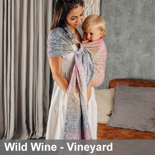 Woman carries baby on her front in Lenny Lamb Ring Sling in Wild Wine Vineyard fabric