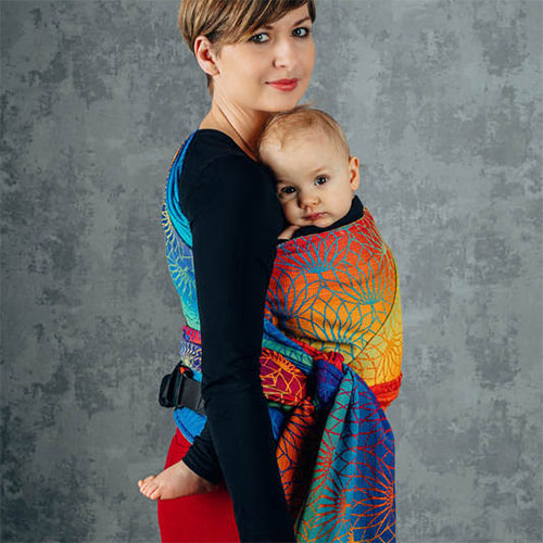 Woman carrying baby on her front in Lenny Lamb Lenny Hybrid Half Buckle Baby Carrier in Rainbow Lotus