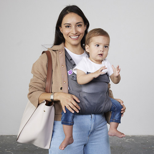 Woman carries baby facing forwards in Izmi Breeze Baby Carrier