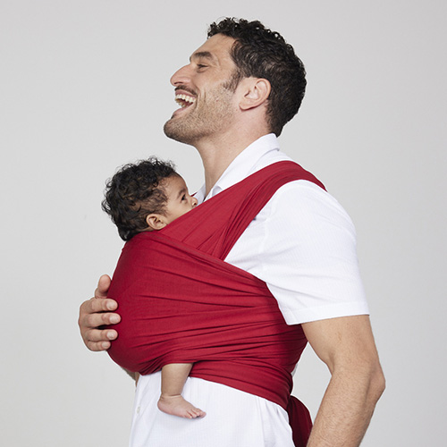 Man carries baby on his front in Izmi Baby Wrap in Red